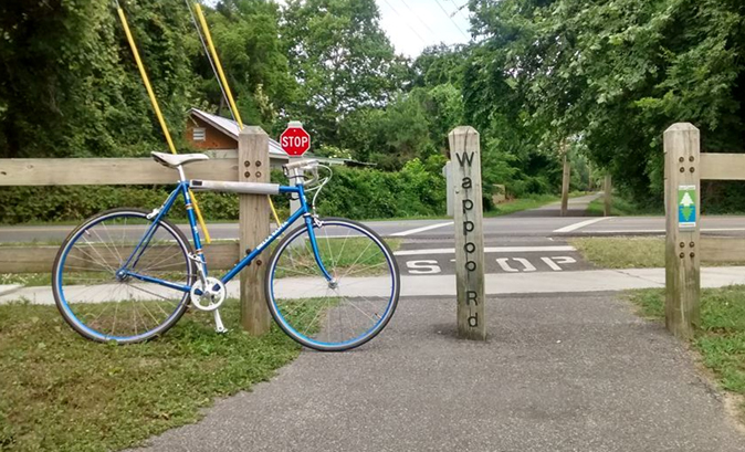 A bicycle parked in front of the greenway entrance.