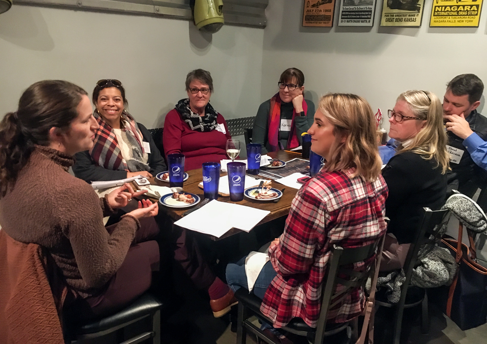 A group of educators at a restaurant table having a discussion.