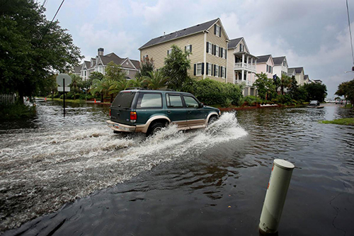 A car drives through a flooded Charleston street.